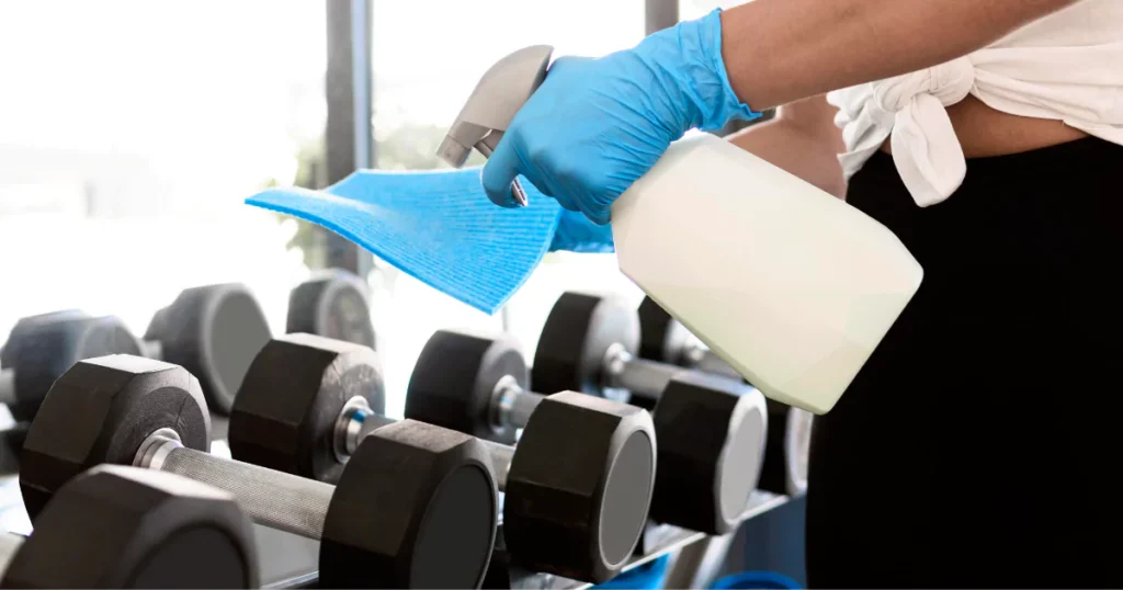 Kézi súlyzók alapos fertőtlenítése egy privát fitnesz stúdióban a maximális higiénia érdekében.
